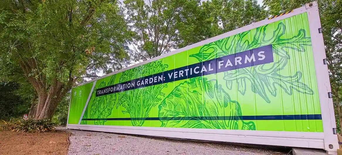 Long white shipping container brightly branded with "VERTICAL FARMS" graphic, used for high-tech agriculture.