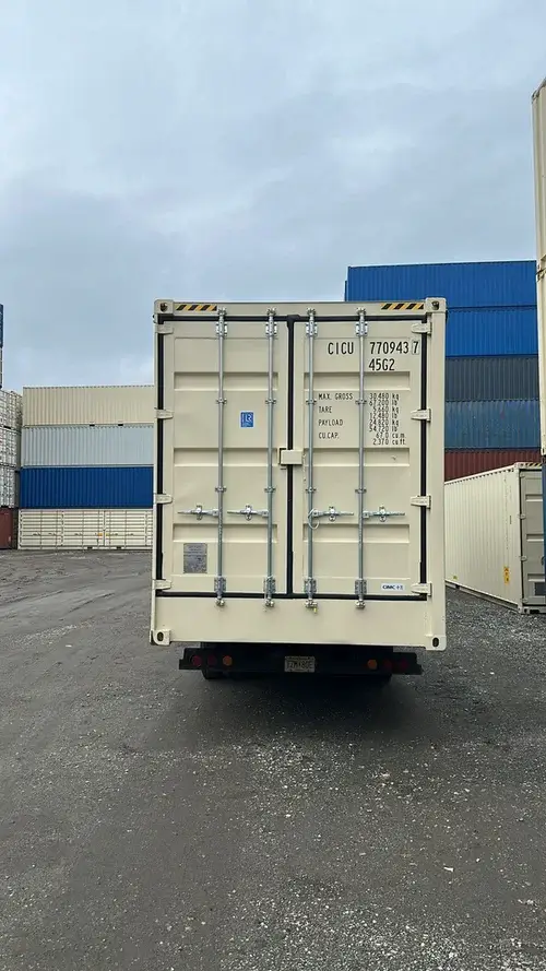 40ft high cube full open side shipping container being transported on a flatbed truck – front view