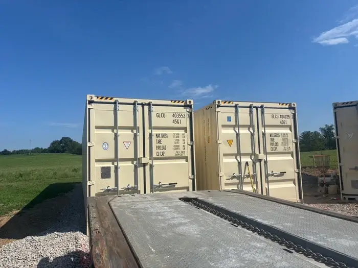 Two beige shipping containers being transported 