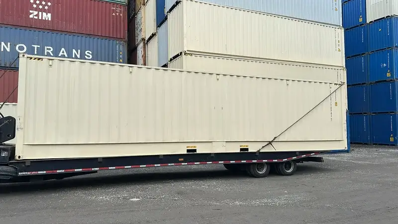 40ft high cube open side shipping container being delivered on a flatbed truck in Baytown, TX – side view