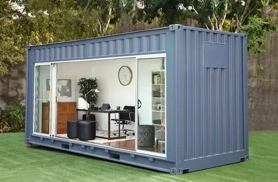 Modern 20ft shipping container office with large glass sliding doors, furnished interior, and AC unit in a grassy area.