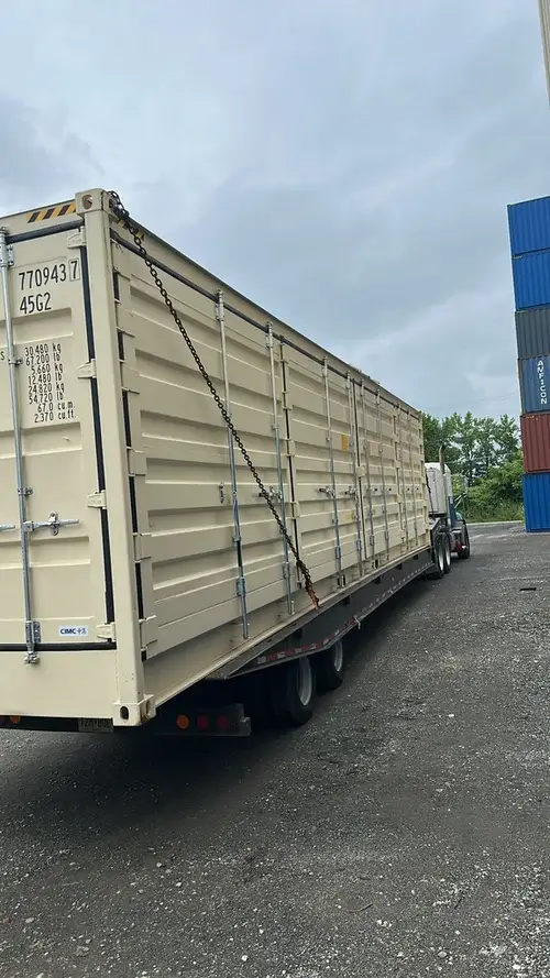 40ft high cube shipping container being transported on a flatbed truck 