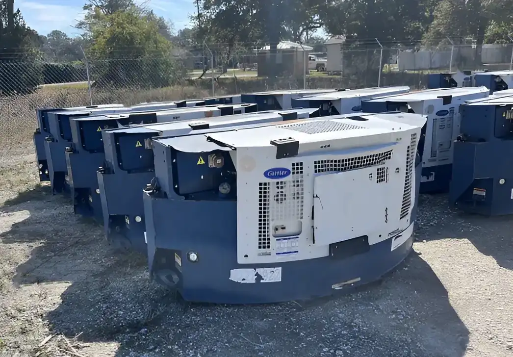 A group of used Carrier refrigeration units stacked in an outdoor storage area, ready for use with refrigerated containers or trailers.