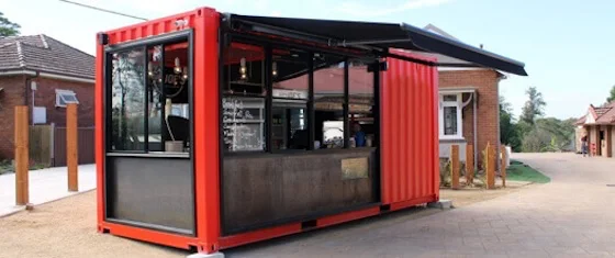 Modern red shipping container retail kiosk with a large service window and awning, designed for use as a cafe or food vendor.