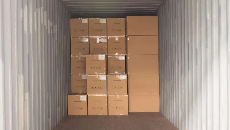 Interior view of a shipping container packed nearly full with neatly stacked cardboard boxes and cartons for storage.